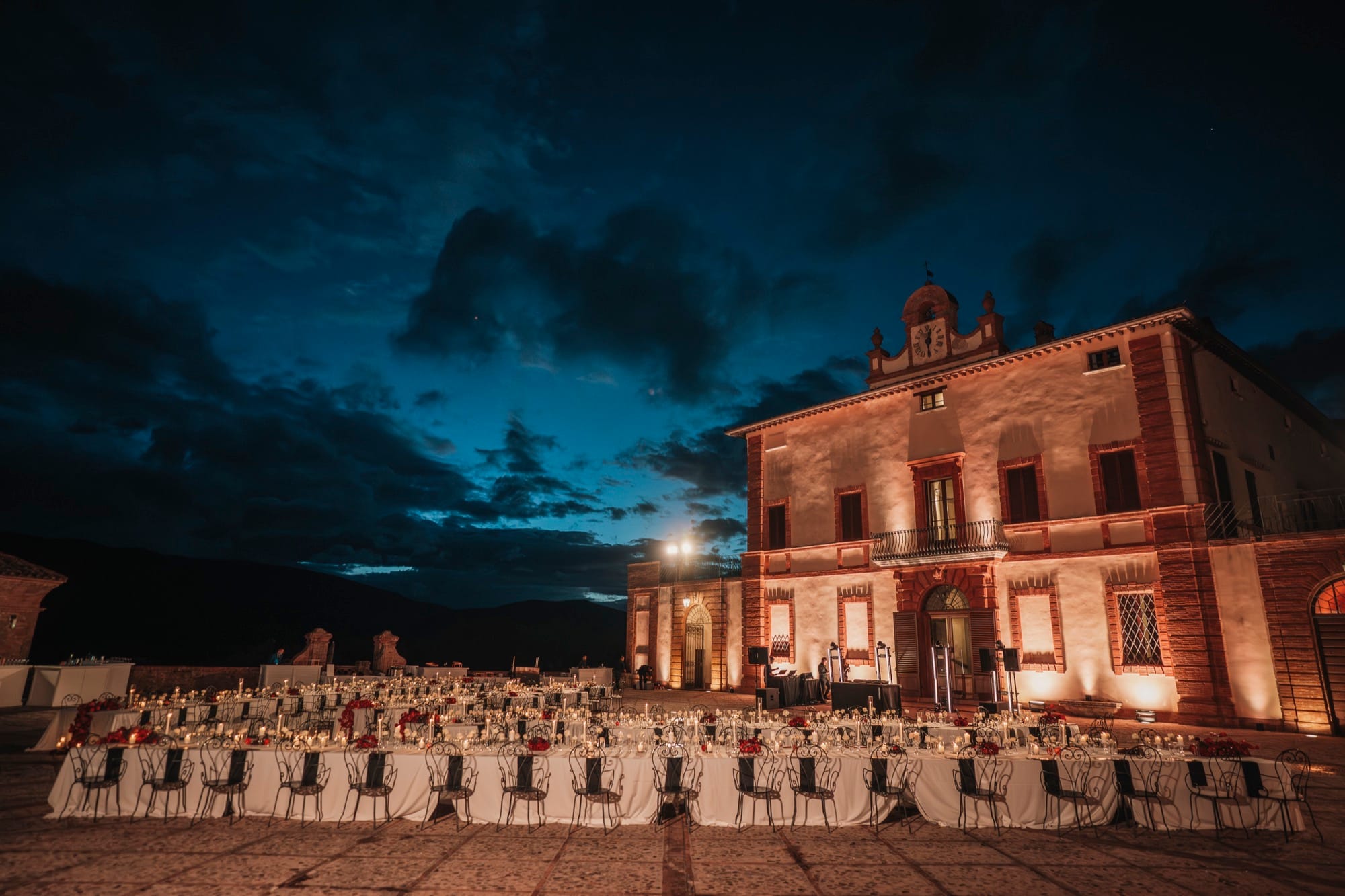 A villa lit up at night, with tables set for a group dinner